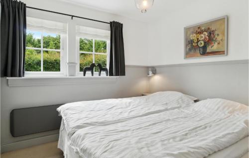 a bedroom with a white bed and a window at Tisvildelund in Vejby