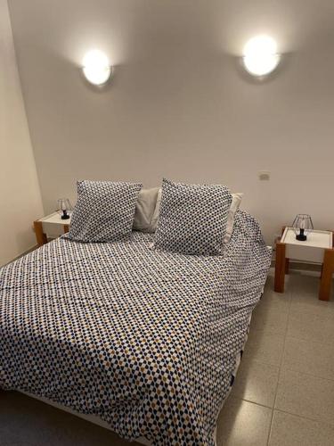 a bedroom with a bed with two pillows and two tables at Charmant logement proche de la mer in Florensac