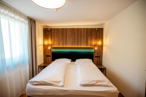 a bedroom with a large white bed with a wooden wall at Moseralm Dolomiti Spa Resort in Nova Levante