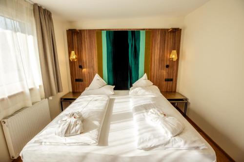 a bedroom with a bed with white sheets and towels at Moseralm Dolomiti Spa Resort in Nova Levante