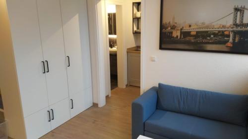 a living room with a blue couch and a white cabinet at Frisch renoviertes Appartement in Mönchengladbach