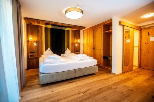a bedroom with a bed in a room with wooden floors at Moseralm Dolomiti Spa Resort in Nova Levante