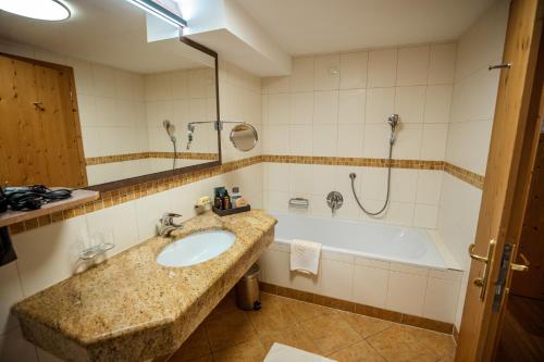 a bathroom with a sink and a bath tub at Moseralm Dolomiti Spa Resort in Nova Levante