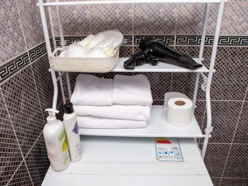 uma prateleira com toalhas e produtos de higiene pessoal na casa de banho em Студия в центре города, в «Золотом квадрате» em Almaty