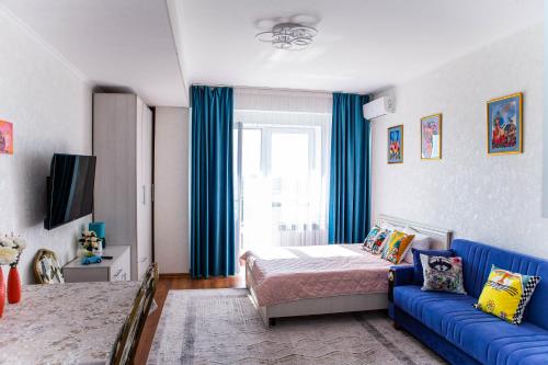 um quarto com uma cama e um sofá azul em Студия в центре города, в «Золотом квадрате» em Almaty