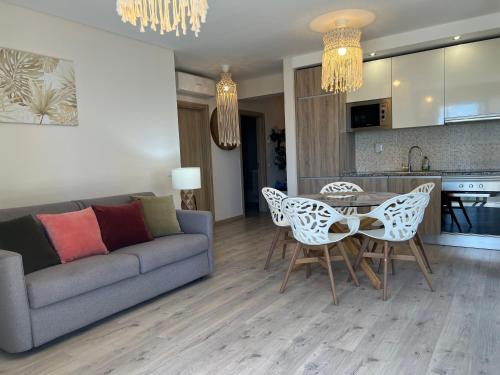 a living room with a couch and a table and chairs at McRamé Design Apt Sea View, Beachfront, Swimming Pool, 2BDR, 2BAR, 6 pax, Praia da Rocha in Portimão