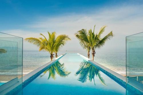 a swimming pool with palm trees and the ocean at Harbor 3008 Amazing beach front condo by Moikkarentals in Puerto Vallarta