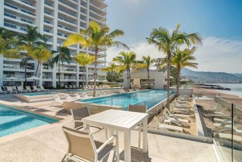 a pool with chairs and a table next to a building at Harbor 3008 Amazing beach front condo by Moikkarentals in Puerto Vallarta