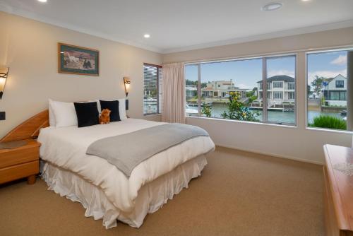 Sunset View - Pauanui Waterfront Home في باوانوي: غرفة نوم بسرير كبير ونافذة كبيرة