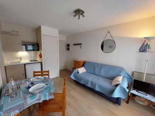 un salon avec un canapé bleu et une table dans l'établissement Charmant T2 au cœur de Saint-Palais-sur-Mer, à deux pas du marché et de la plage - FR-1-550-66, à Saint-Palais-sur-Mer