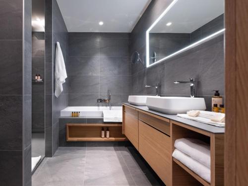 La salle de bains est pourvue d'un lavabo blanc et d'une baignoire. dans l'établissement Chalet contemporain avec piscine privée, sauna et home cinéma à Arc 1800 - FR-1-686-33, à Arc 1800