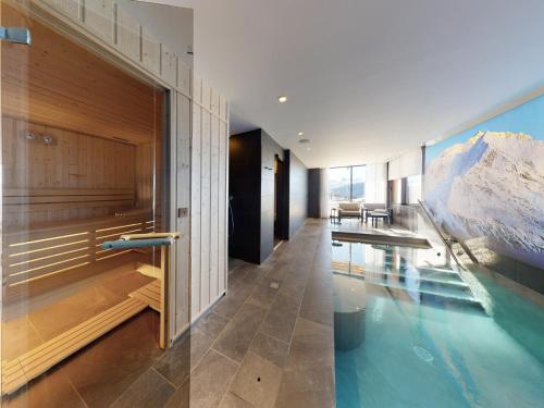 une maison avec une piscine entourée d'une montagne sur le mur dans l'établissement Chalet contemporain avec piscine privée, sauna et home cinéma à Arc 1800 - FR-1-686-33, à Arc 1800