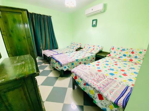 een slaapkamer met 2 bedden en een dambordvloer bij شاليه ٥٣ in Dawwār Ḩalīs