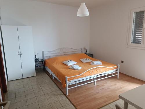 een slaapkamer met een bed met een oranje dekbed bij Apartments Bosnic in Prizba