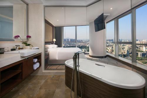 uma casa de banho com uma cama, uma banheira e um lavatório. em Sheraton Nanjing Kingsley Hotel & Towers em Nanquim