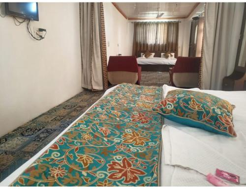una habitación de hotel con una cama con una manta colorida en Hotel Shafaaf Plaza, Srinagar en Srinagar