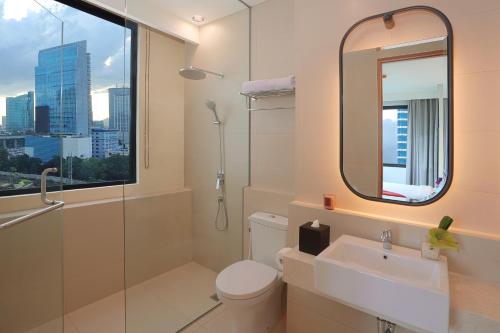 a bathroom with a toilet and a sink and a mirror at Citadines Gatot Subroto Jakarta in Jakarta