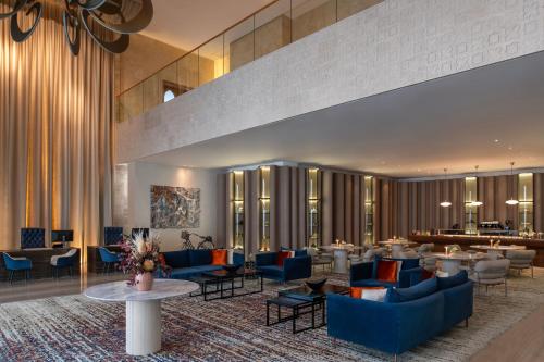 a hotel lobby with blue couches and tables at Abesq Doha Hotel and Residences in Doha