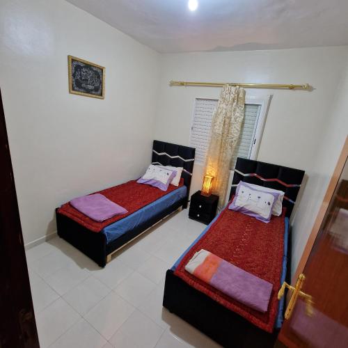 een slaapkamer met 2 bedden en een lamp erin bij appartement les Jardins de la Moulouya in Saidia 