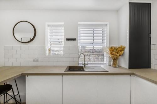 a kitchen with white cabinets and a sink and a mirror at NEW Stunning Plymouth Central Apartment - Sleeps 6 in Plymouth
