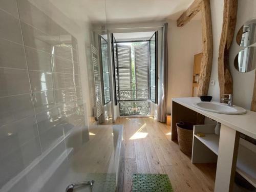 y baño con bañera, lavabo y espejo. en Maison gîte tranquille et nature., en Verdun-en-Lauragais