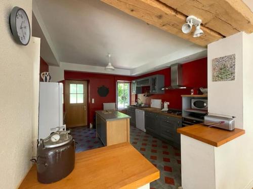cocina grande con paredes rojas y encimera en Maison gîte tranquille et nature., en Verdun-en-Lauragais