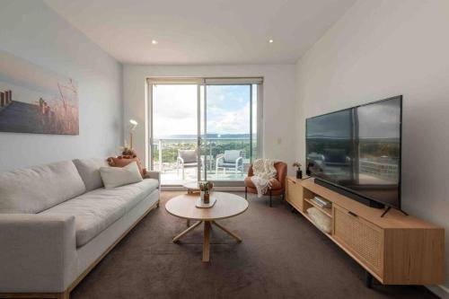 a living room with a couch and a flat screen tv at City apartment, pool & carpark in Adelaide