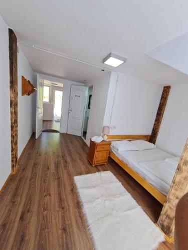 a room with two beds and wooden floors at Cabana Floare de stâncă Retezat cu Ciubar in pădure in Hunedoara