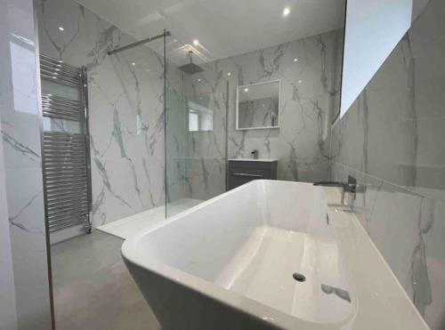 a bathroom with a large white tub and a shower at Large Countryside House Swim Pool Jacuzzi Sleeps 10 guest in Ware