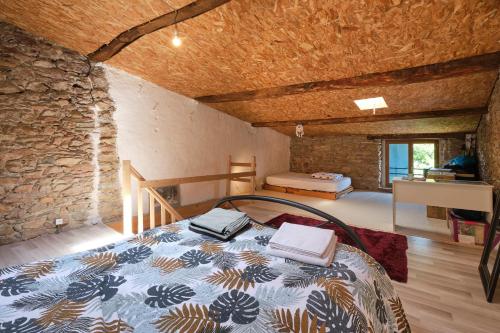 La Maison Occitane - Charmante maison pour 4 في Caunes-Minervois: غرفة نوم بسرير وجدار حجري
