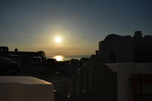 a sun setting over the ocean with cars parked at Casa Di Villagio in Pirgos
