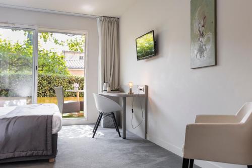 a bedroom with a bed and a desk and a window at Le Carré d'Alethius Logis Hôtel Restaurant in Charmes-sur-Rhône