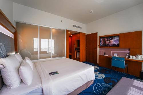 a hotel room with a large bed and a television at Novotel Fujairah in Fujairah