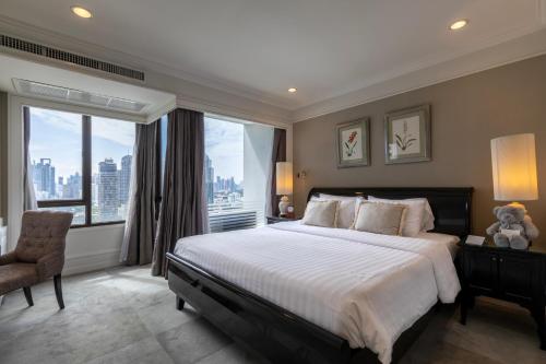 een slaapkamer met een groot bed en een groot raam bij Cape House Langsuan Hotel in Bangkok