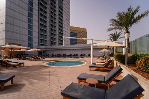 a pool with chairs and umbrellas in a hotel at Novotel Fujairah in Fujairah