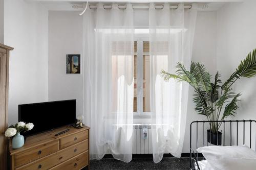 a bedroom with a window with white curtains and a tv at Liguria Home in Vado Ligure