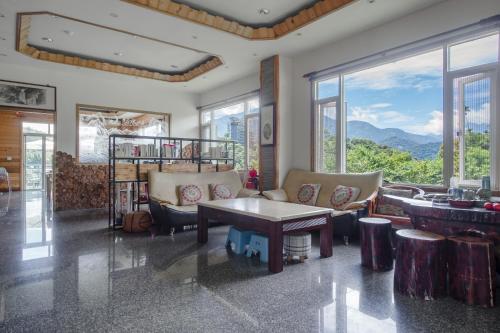 a living room with a table and chairs and windows at Bishui Shanju Lakeside B&B in Yuchi
