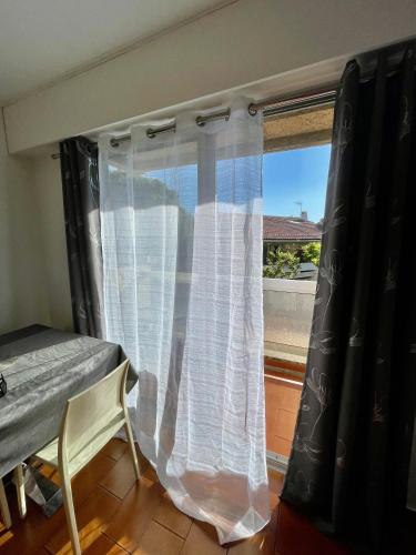 uma janela com uma cortina branca e uma mesa e cadeira em Studio Plage em Marselha