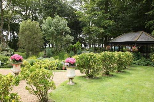 a garden with two vases filled with pink flowers at Hunday Manor Country House Hotel in Workington