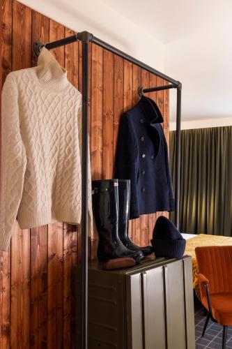 a wardrobe with a sweater and a coat and boots at Best Western Plus Hotel Cargo in Dunkerque