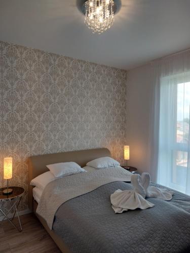 Paskom Apartmanház في Nyergesújfalu: غرفة نوم عليها سرير وبجعة