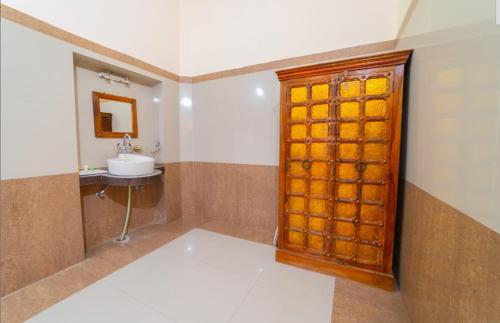 a bathroom with a sink and a wooden door at Sisodia Hotel & Resorts in Jodhpur