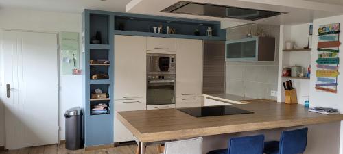 eine Küche mit einem Holztisch und blauen Schränken in der Unterkunft La mouette in Ploeren