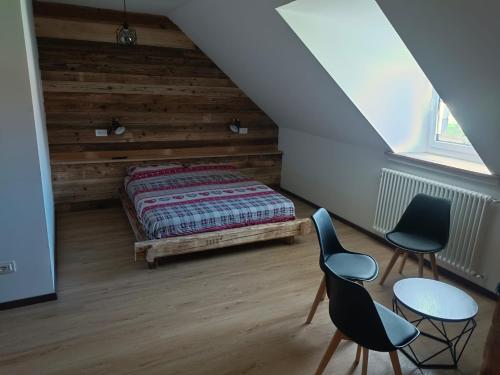 Schlafzimmer im Dachgeschoss mit einem Bett und 2 Stühlen in der Unterkunft AlBy&B in Arnoldstein