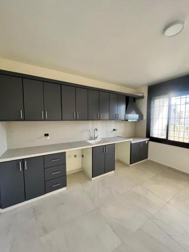 a large kitchen with black cabinets and a sink at German-Palestinian Appartement in Al Khalīl