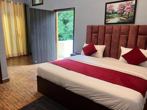 1 dormitorio con 1 cama grande con almohadas rojas en The HeartWood Farms Inn, en Rāmnagar