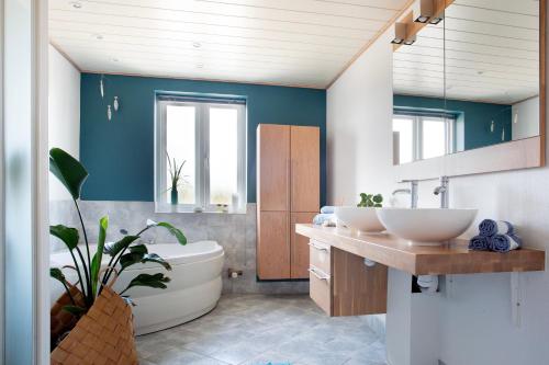 La salle de bains est pourvue de 2 lavabos et d'une baignoire. dans l'établissement Stone Mountain BnB, à Stenbjerg