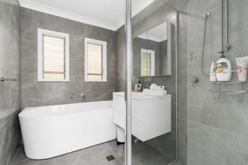 a bathroom with a white tub and a shower at Coastal Cottage Batemans Bay in Batemans Bay