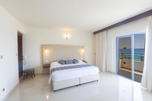 a bedroom with a bed and a view of the ocean at Iliada Beach Hotel in Protaras