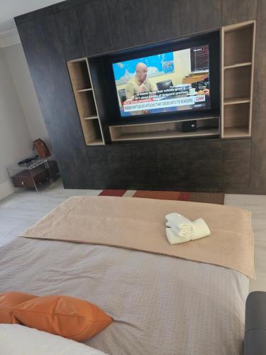 a room with a tv and a bed with a towel at Luxury Room in Harold Wood
